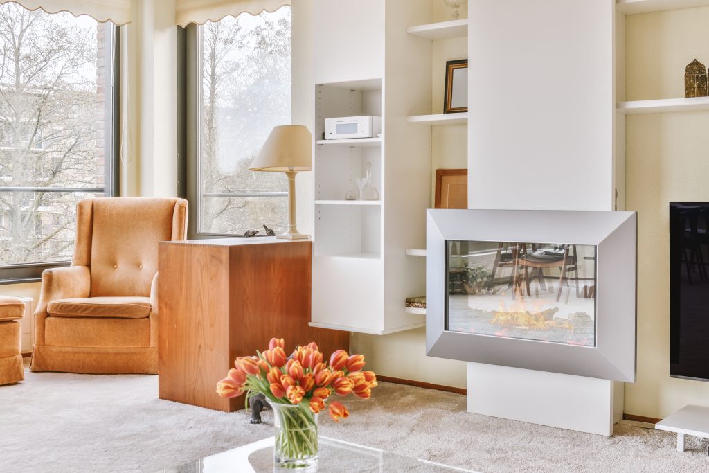 Decoration of a spacious living room with a glazed fireplace and flowers in a modern apartment