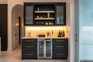 Luxury bar cabinetry with black base, glass shelving, and warm underlighting.