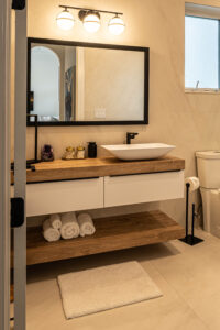 Floating bathroom vanity with vessel sink, tile wall, and under-shelf towel storage.