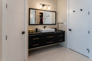 Vanity bathroom with black cabinets and backlit mirrors.