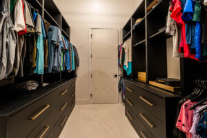 Spacious walk-in closet with black cabinetry, drawers, and hanging space.