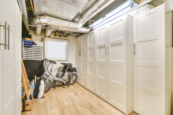 Custom-built storage in utility room with HVAC equipment and light wood cabinetry