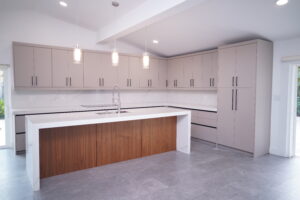 Minimalist kitchen design with wood base cabinets, white uppers, and waterfall island.