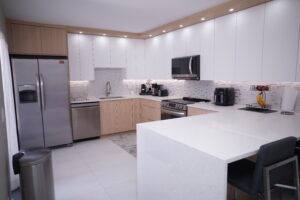 Contemporary kitchen with L-shaped layout, quartz counters, and sleek appliances.