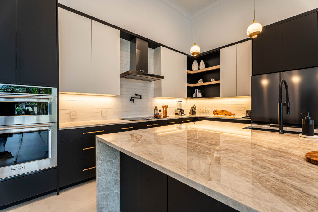 Full kitchen view in Deerfield Beach with bold black cabinets, under-cabinet lighting, and premium finishes throughout. Corner kitchen with open wood shelving and clean lines.
