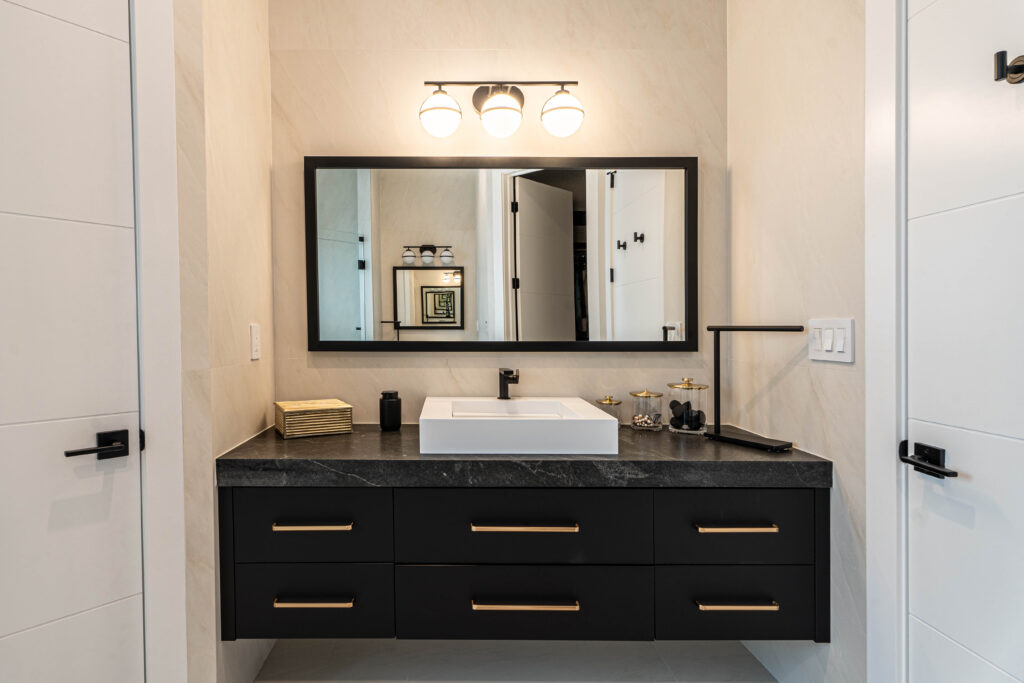 Custom black bathroom vanity with brass handles, white vessel sink, and large framed mirror in a modern, minimalist bathroom design. Modern guest bathroom with black vanity, wall-mounted mirrors, and neutral tile.