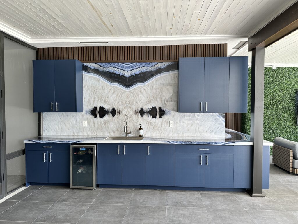 Transitional kitchen with blue base cabinets, marble backsplash, and abstract art.