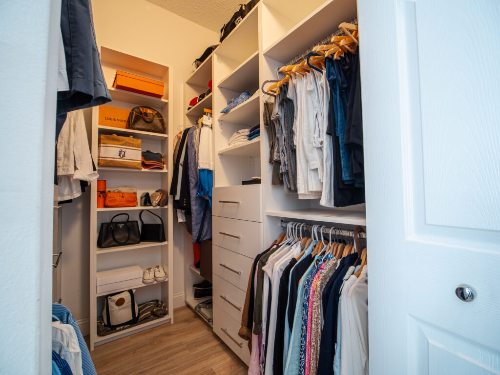Custom walk-in closet with dual hanging rods, shelving, and wood flooring.