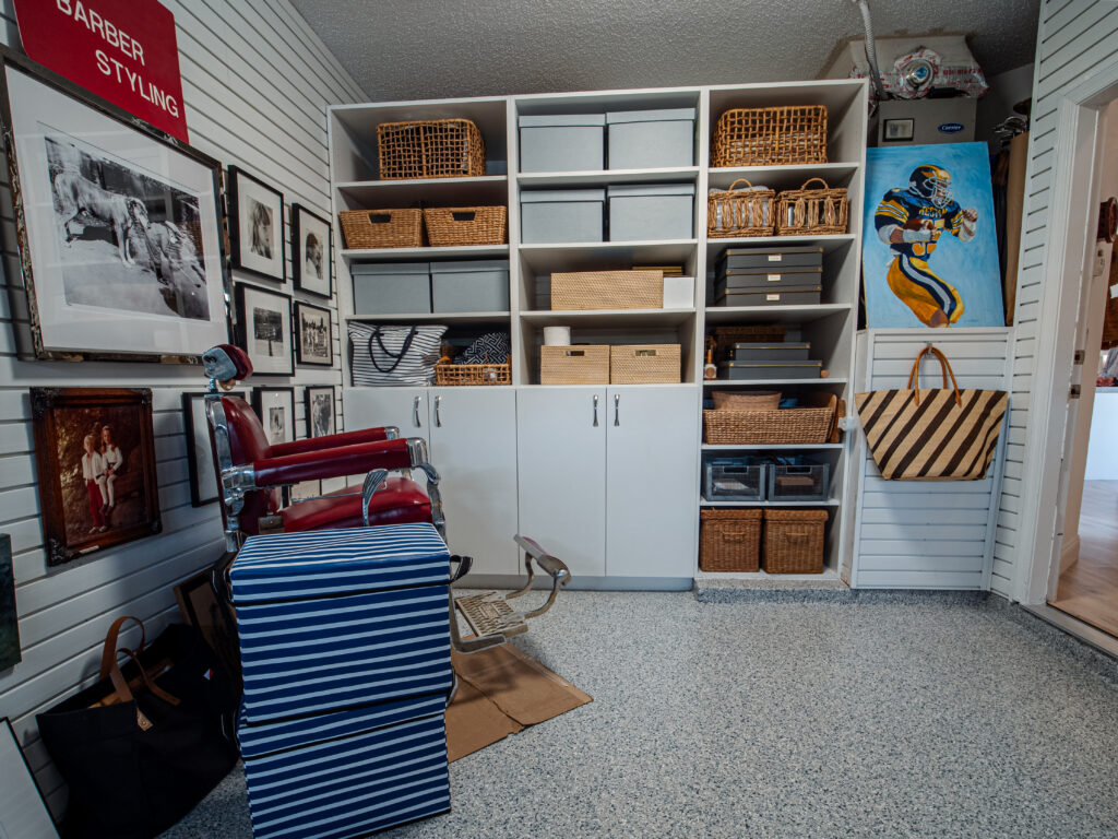 Garage with custom storage cabinetry and wall-mounted shelving in complete home remodel in Boynton Beach.