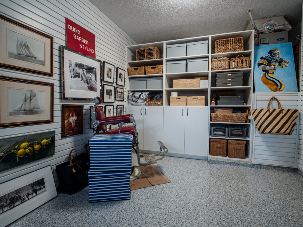 Luxury garage in South Florida. Functional home storage with white cabinets, framed art, and organized bins.