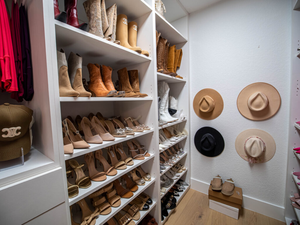 Boutique-style walk-in closet Boca Raton. Custom closet with vertical shoe storage and hat display in a modern walk-in layout.