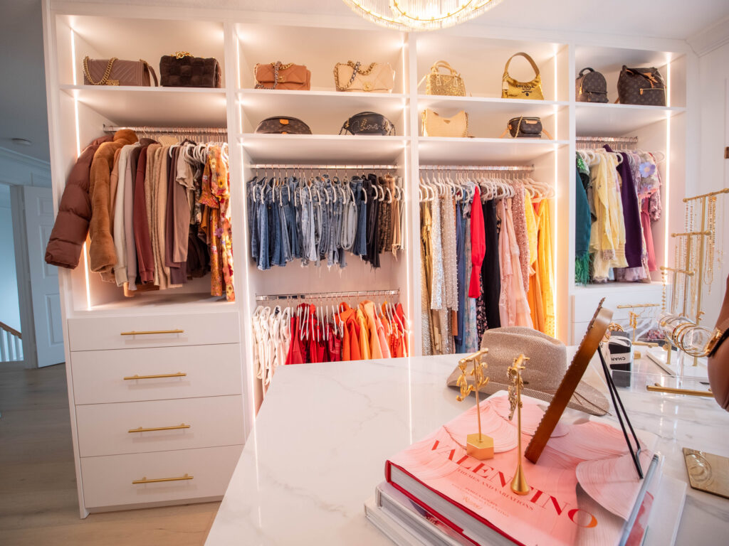 Custom closet in Boynton Beach with gold handles. Walk-in closet with built-in shelving, central island, and warm lighting.