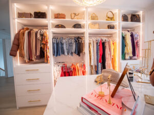 Custom closet in Boynton Beach with gold handles. Walk-in closet with built-in shelving, central island, and warm lighting.