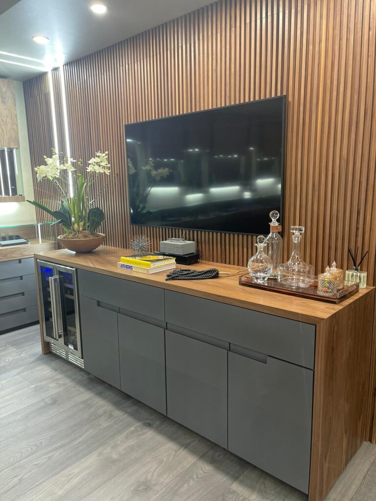 Modern media wall with wood slats, gray cabinetry, and decor bar setup.
